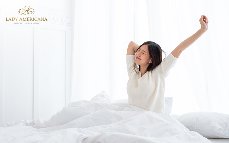 Woman happily waking up from a nap after choosing a bed with proper spinal support